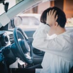 車の中で頭を抱えている女性